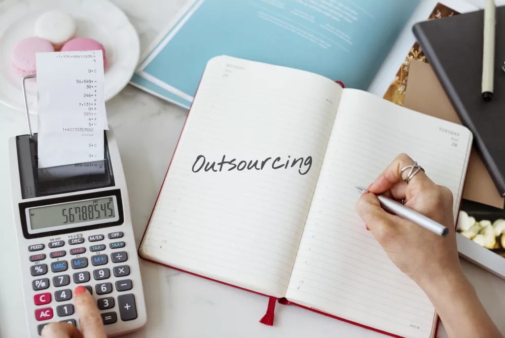 Outsourcing written in a notebook and a calculator on the side
