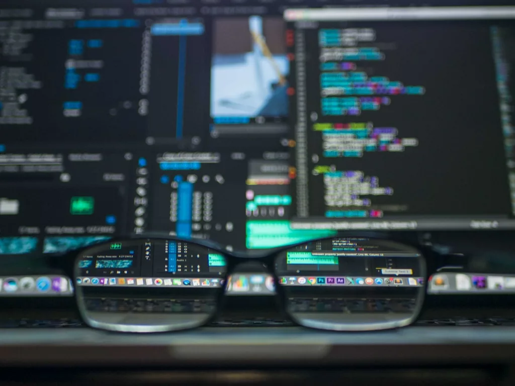 glasses in front of a screen filled with code